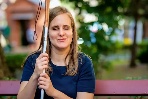 vision-impaired-woman-with-cane-smiling-and-sitting-on-park-bench.webp