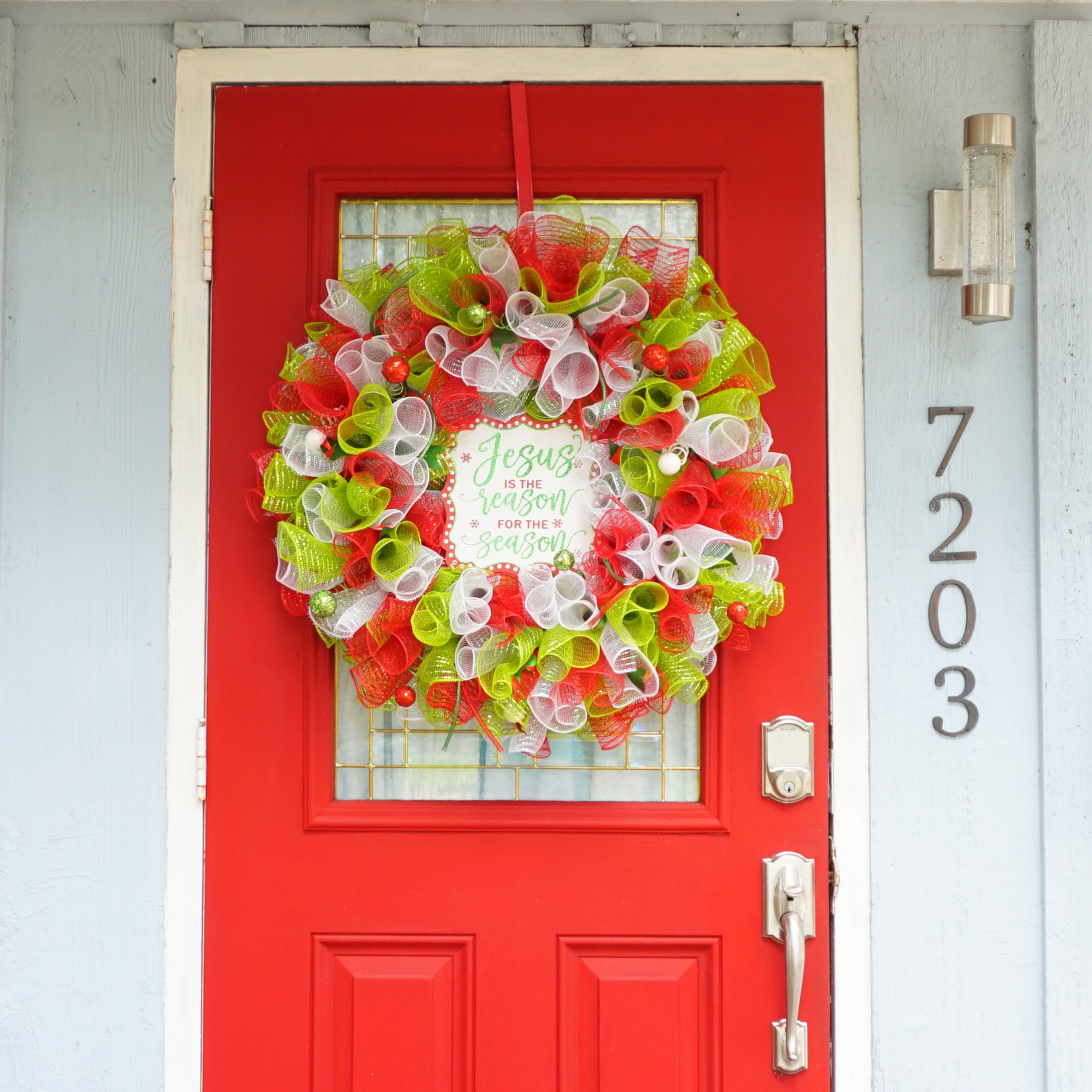 close up of red white and green Whimsical styled Jesus is the Reason for the Season Deco Mesh Wreath on front door