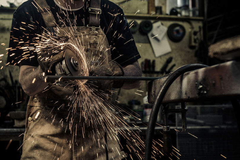 Een man slijpt met zijn slijptol een stuk ijzer. Een vuurregen komt van het ijzer af. Er zijn een hoop vonken. A man sharpens a piece of iron with his grinding tool. A rain of fire comes from the iron. There are a lot of sparks.
