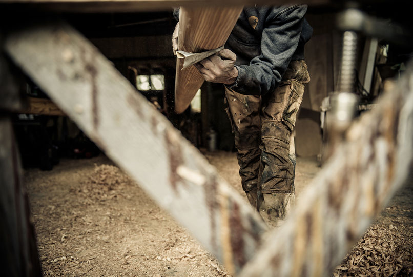 Een ambachtsman schuurt de onderkant van een mast. A craftsman sands the bottom of a mast.