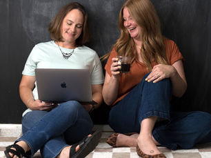 Jen & Karyn of Link & Layer seated with a computer and coffee reviewing new branded photos for their website. 