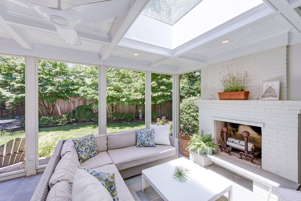 White couch in sun room with fireplace with blue and green pillows, photo by Mary Pat Collins.