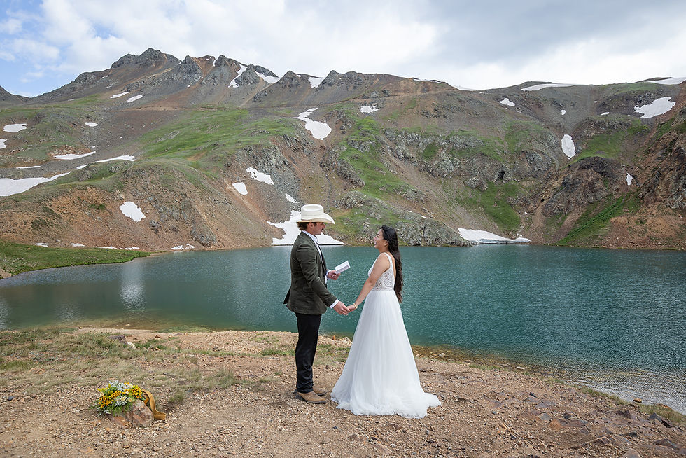 Bride and groom reading their vows beside the turquoise waters of Lake Como in the San Juan Mountains during their off-road elopement adventure.