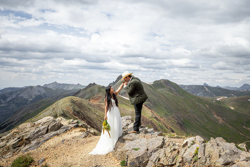 Groom kissing the bride’s hand during a quiet moment in the San Juan Mountains, surrounded by rugged terrain during their off-road Colorado elopement.