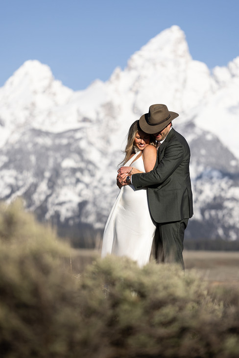 Bride and groom exchanging vows at sunrise at Schwabacher's Landing with alpenglow on the Grand Tetons