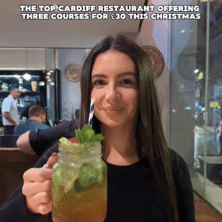 Woman smiling and holding a drink with mint and a straw in a restaurant. Text above reads: "The top Cardiff restaurant offering three courses for £30 this Christmas."