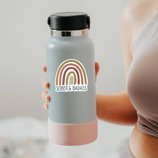 Thumbnail: Woman holding water bottle with muted earthy toned rainbow with "Sober and badass"