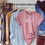 Thumbnail: rose colored shirt with semi colon heartbeat and heart on a wood hanger on a rack of clothes.