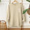 Thumbnail: tan crewneck hanging on wood hanger with "you belong with the wild flowers" on the front over the chest.