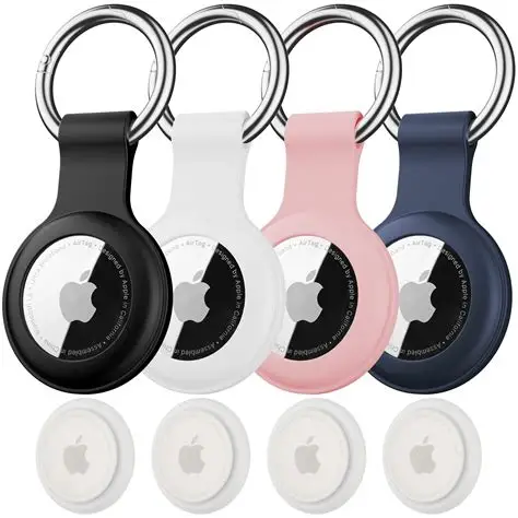 Set of Apple AirTags with black, white, pink, and blue keychain holders.