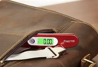 Red digital luggage scale showing zero weight on display next to brown bag.