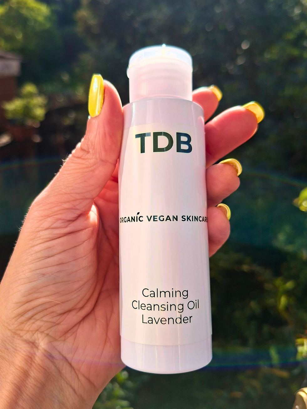 Thumbnail: Hand holding a bottle of Makeup Botanical Primer by Third Day Botanics next to plant