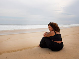 Woman sitting in the sand by the ocean. By Freepik