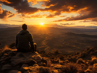 A man sitting on a rock watching the sunset