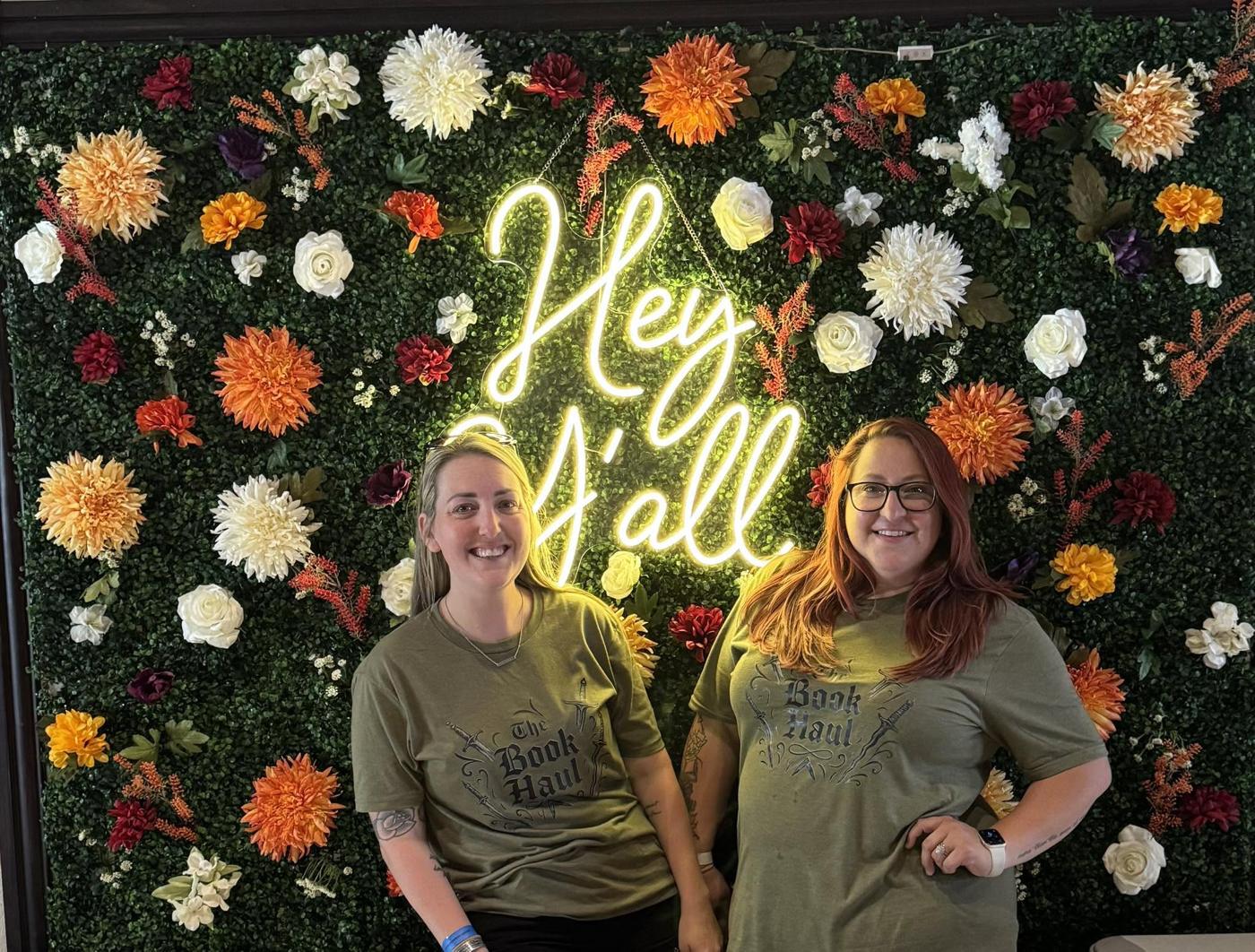 The Book Haul team in front of a neon sign