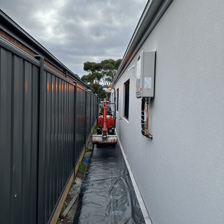 Small excavator in a narrow side passage during renovation.