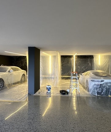 Modern luxury garage with three cars and sleek black pillars.
