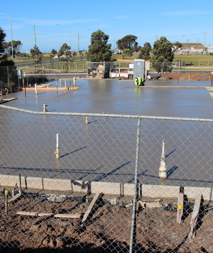 Freshly poured concrete foundation at a construction site.