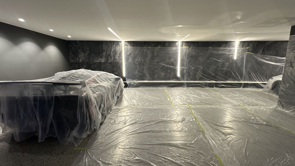 Car covered in plastic inside a modern dark garage