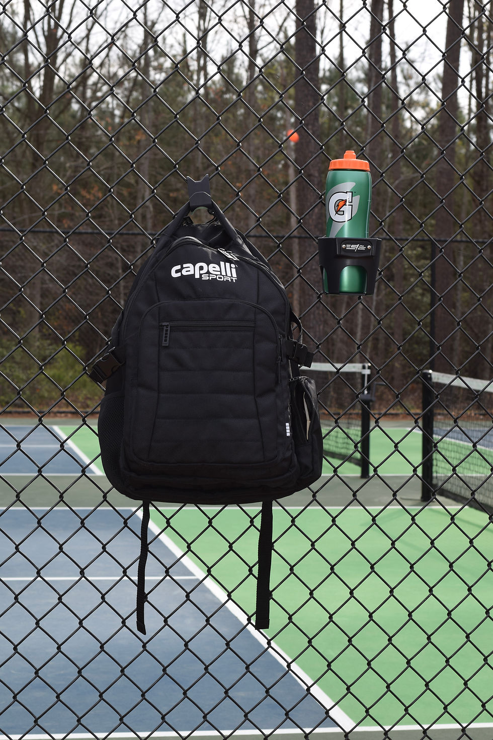 Thumbnail: Backpack hanging on fence hook next to cup holder with sports bottle, organized dugout setup with bag hook for fence