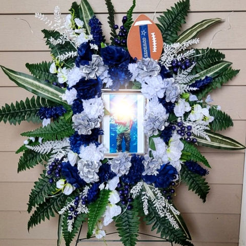 Custom funeral spray with photo and blue and silver flowers.