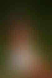 Woman in white dress sitting and smelling purple flowers.