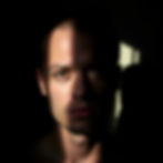 A male face half concealed by shadows