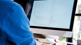Developer working at a computer screen, writing code with AI-assisted development tools