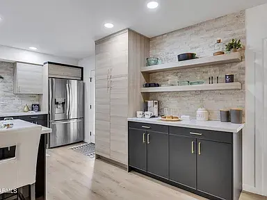 Kitchen transformation in Scottsdale showcasing new cabinets, stone countertops, tile backsplash, and stainless steel appliances.