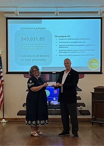 Jeff Quyle, president and CEO of Radius Indiana, presents Brenna LaDuke, the Town Development Coordinator of Borden, with the $49,031 raised for the Borden State Bank building restoration.