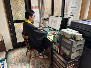 お坊さんの格好で机に向かう司法書士
