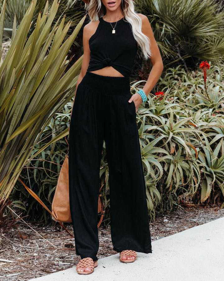 Thumbnail: Woman in black wide leg drawstring pants and crop top.