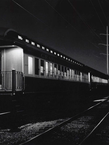 black and white photo of train cars at night. 
