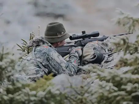 Ein Jäger in Tarnkleidung mit dem Gewehr im Liegendanschlag