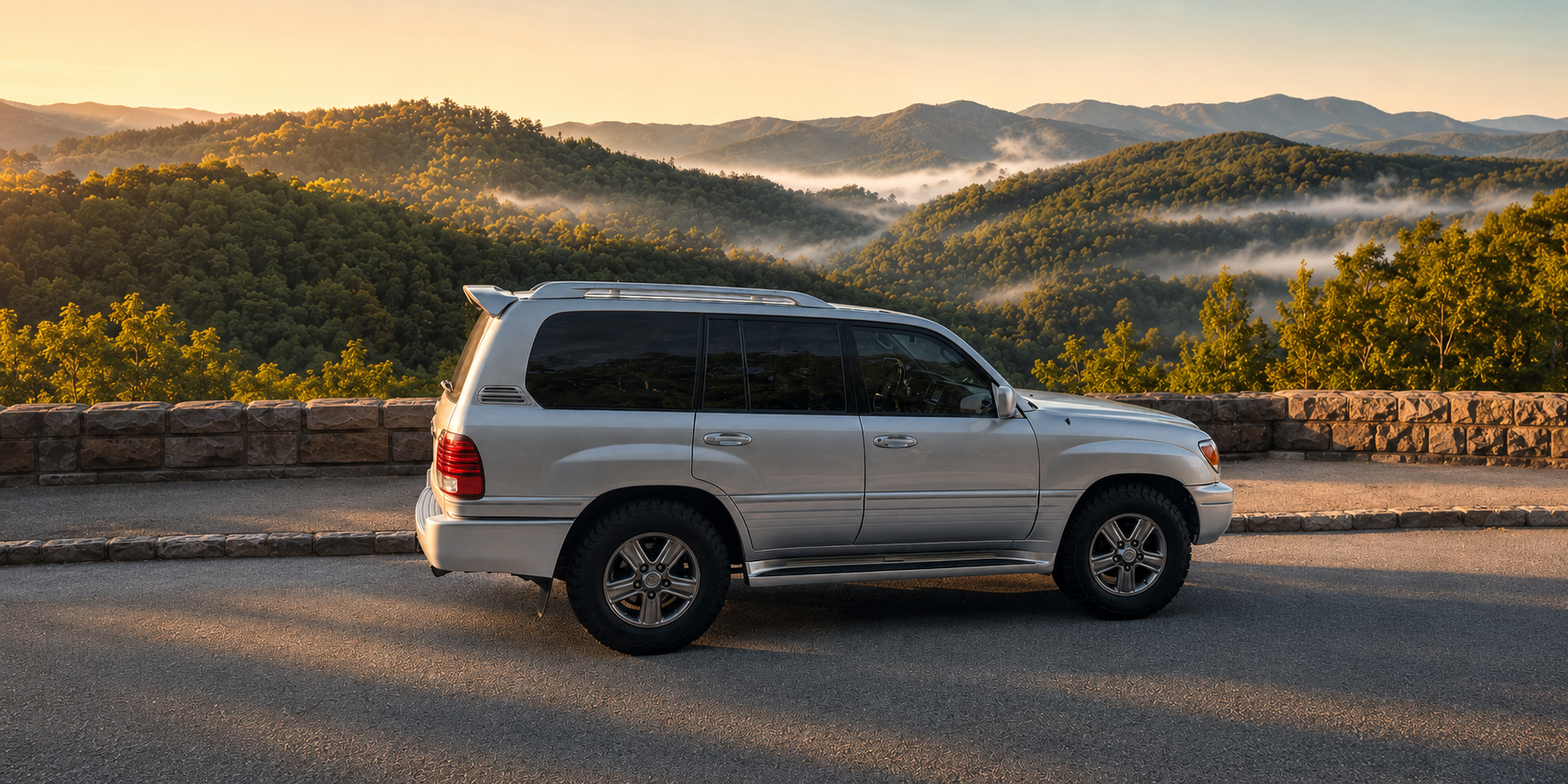 A silver 2007 Lexus LX470 traversing a dusty fire road through the dense green canopy of Cherokee National Forest.