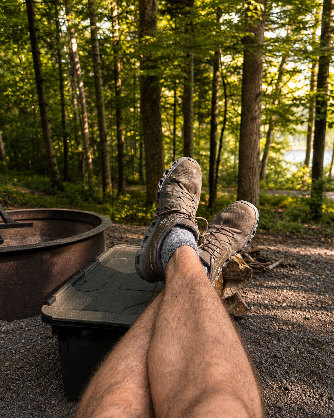 A close-up of a rustic metal coffee dripper resting on a camping mug with steam rising in the crisp morning air.