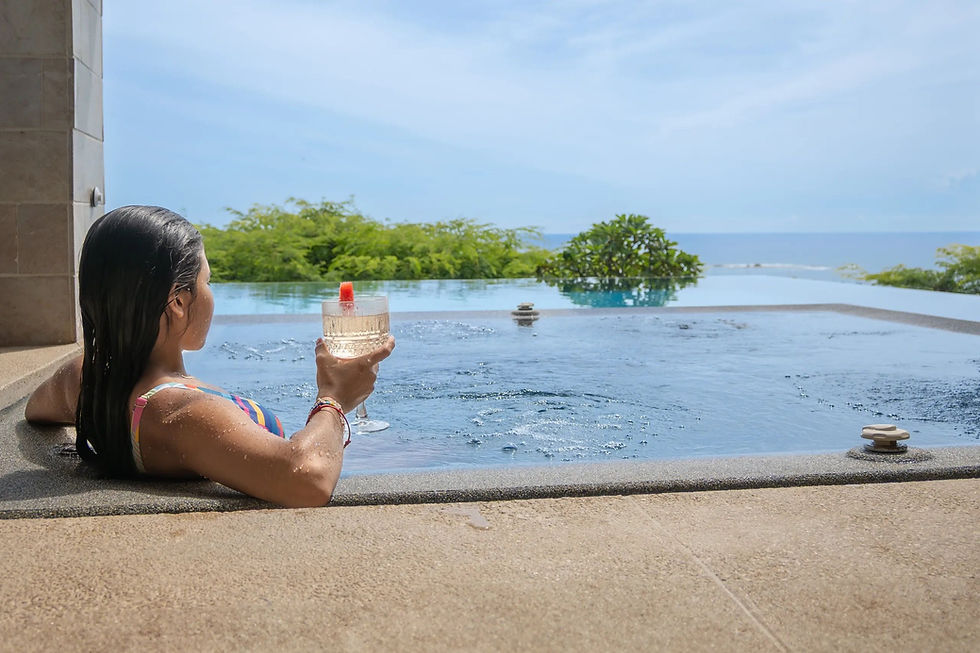 Woman relaxing with a drink by an infinity pool overlooking the ocean at a Costa Rica retreat