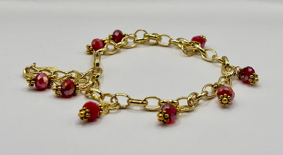 Dainty gold charm bracelet with red crystal drop beads.