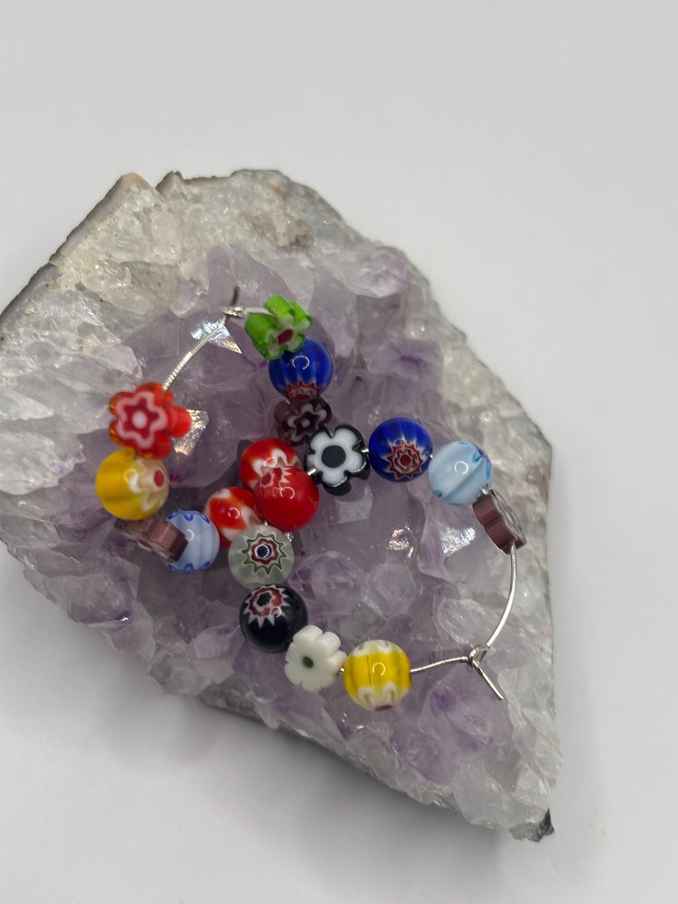 Thumbnail: Colorful Millefiori glass flower hoop earrings on a crystal stone