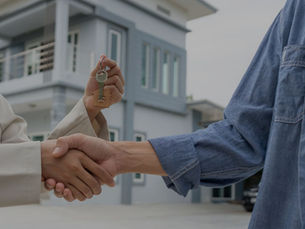 Two people shaking hands, exchanging house keys in front of a modern building. WNY Sell your home fast for cash