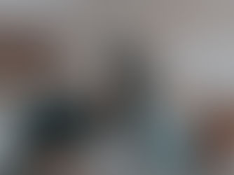 A modern kitchen with teal cabinets, open shelves, and a wooden dining table. It features a stove, microwave, and bar stools.