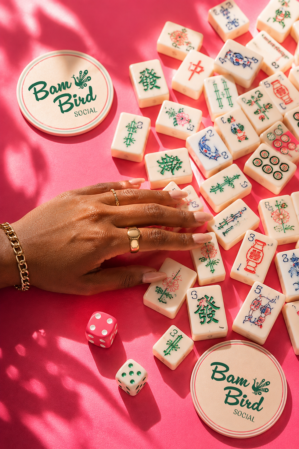 Hand reaching for Bam Bird Social mahjong tiles on pink background