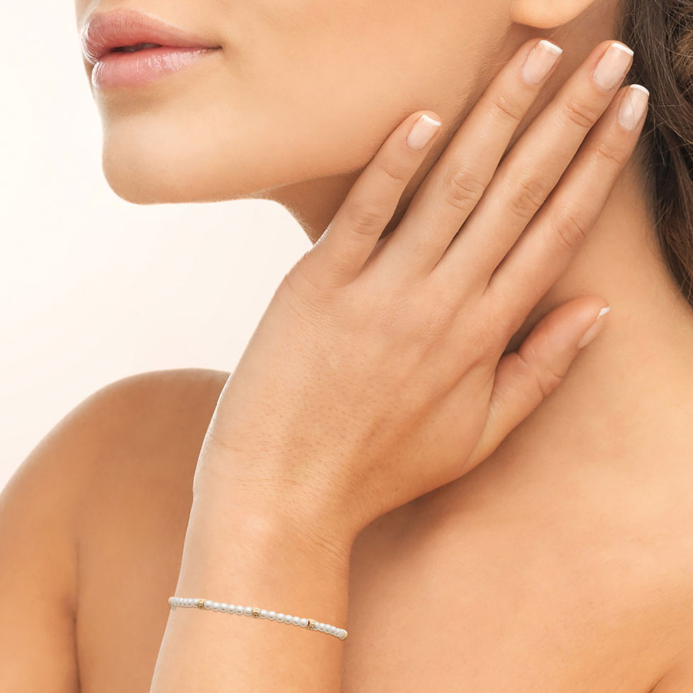 Bracelet en perles blanches avec détails dorés, bijou élégant et intemporel pour femme porté