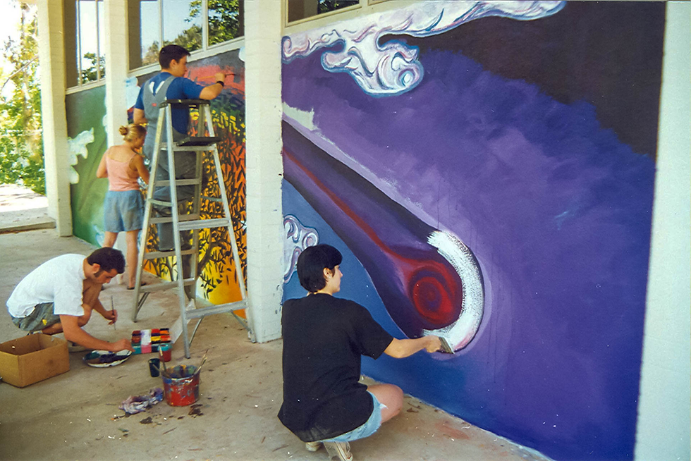 Pitzer College students paint a mural on the walls of a building on campus, as part of its "Campus Aesthetics" public art policy. Photograph by Pitzer College.