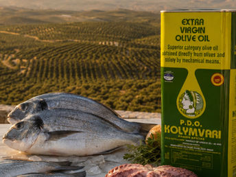 Kolymvari natives Olivenöl extra aus Kreta mit frischem Fisch, Oktopus und mediterranen Kräutern vor kretischen Olivenhainen.