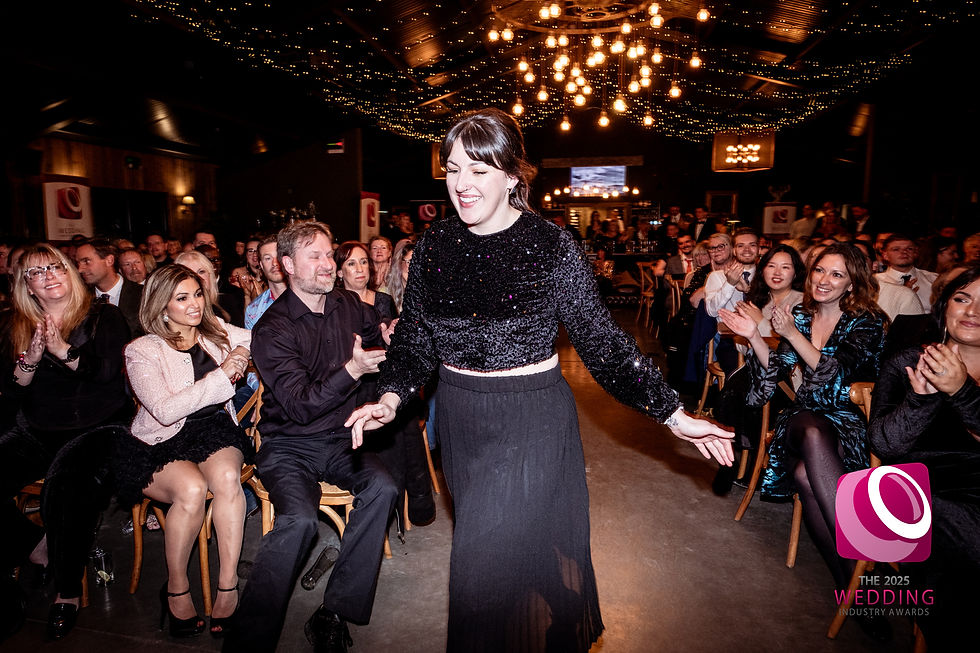 A woman smiles as she walks through an audience to the stage.