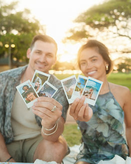 Couple holding pre-printed Polaroids for anniversary gift ideas in Oahu