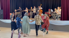 Yiddish folk dancers dancing in front of a stage, with klezmer musicians playing on stage.