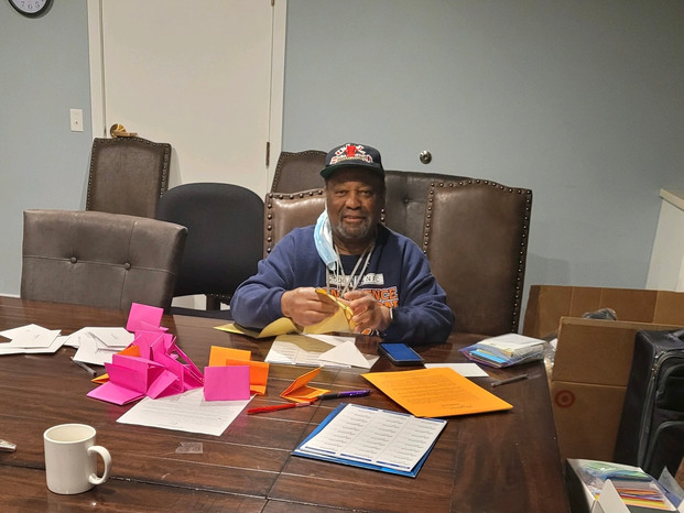 Papa Cheeks stuffing envelopes, sealing seals, and preparing cards for residents of A Safe Place.