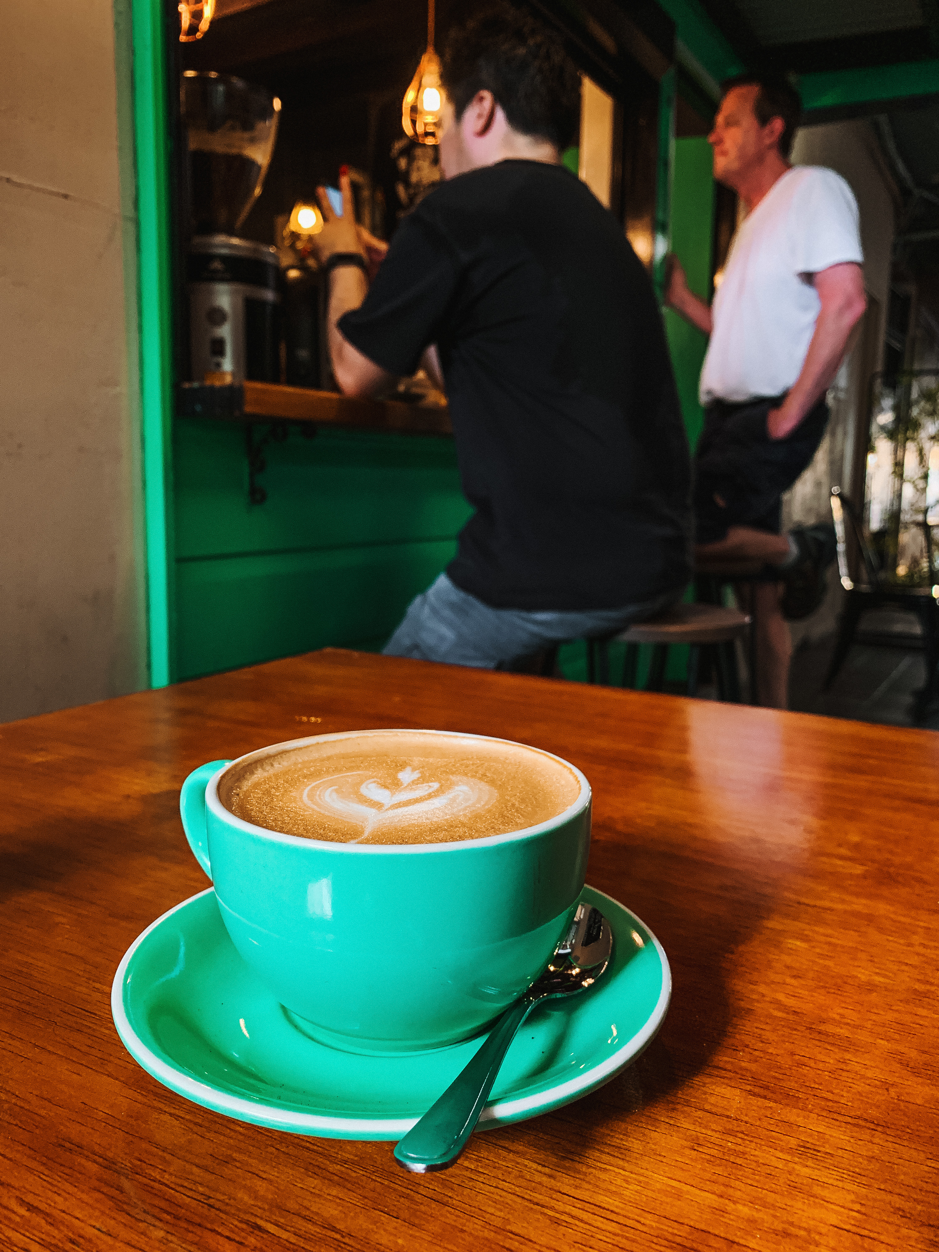 A green Stairwell Coffee cup at the timber coffee counter